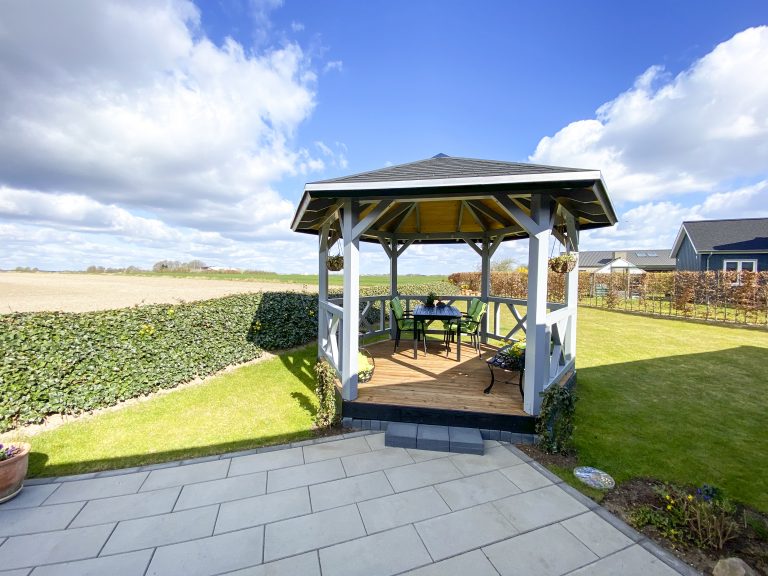 Åben pavillon med udsigt til marker og solnedgang